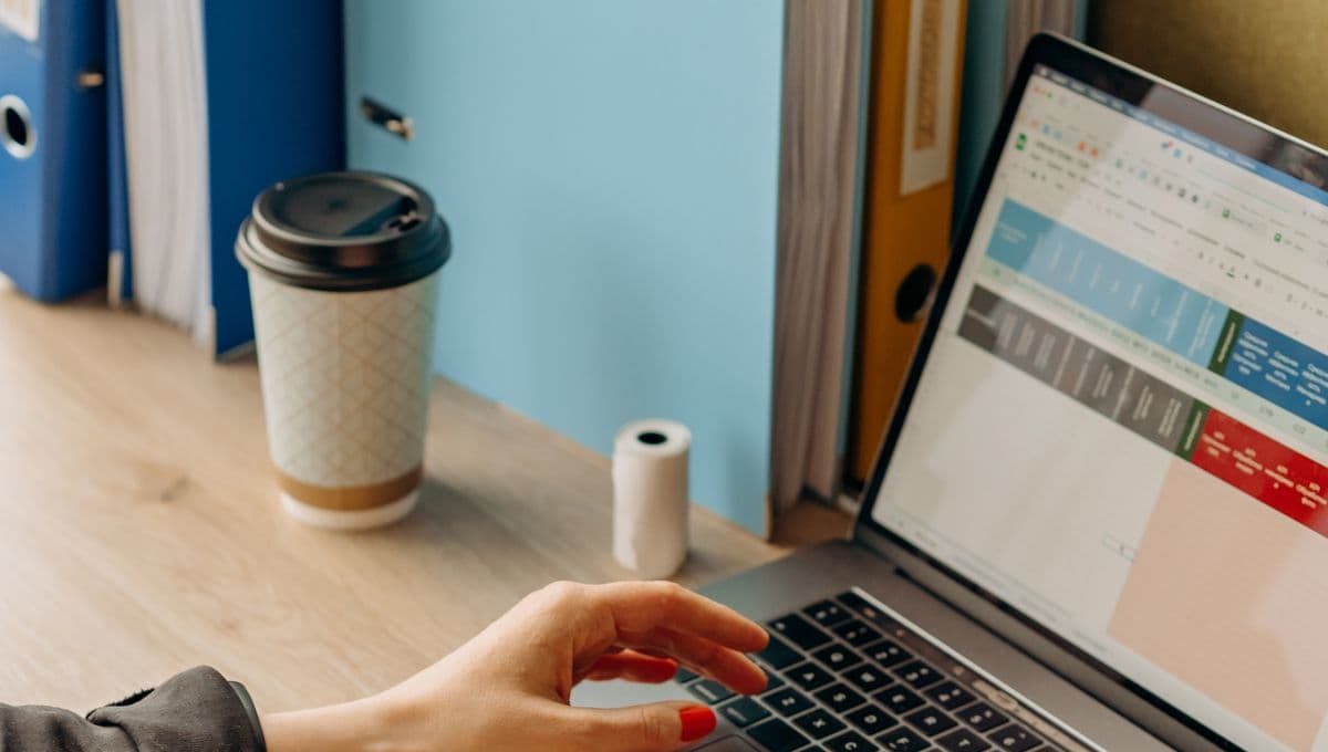 Close-up of hands typing on a laptop at a desk