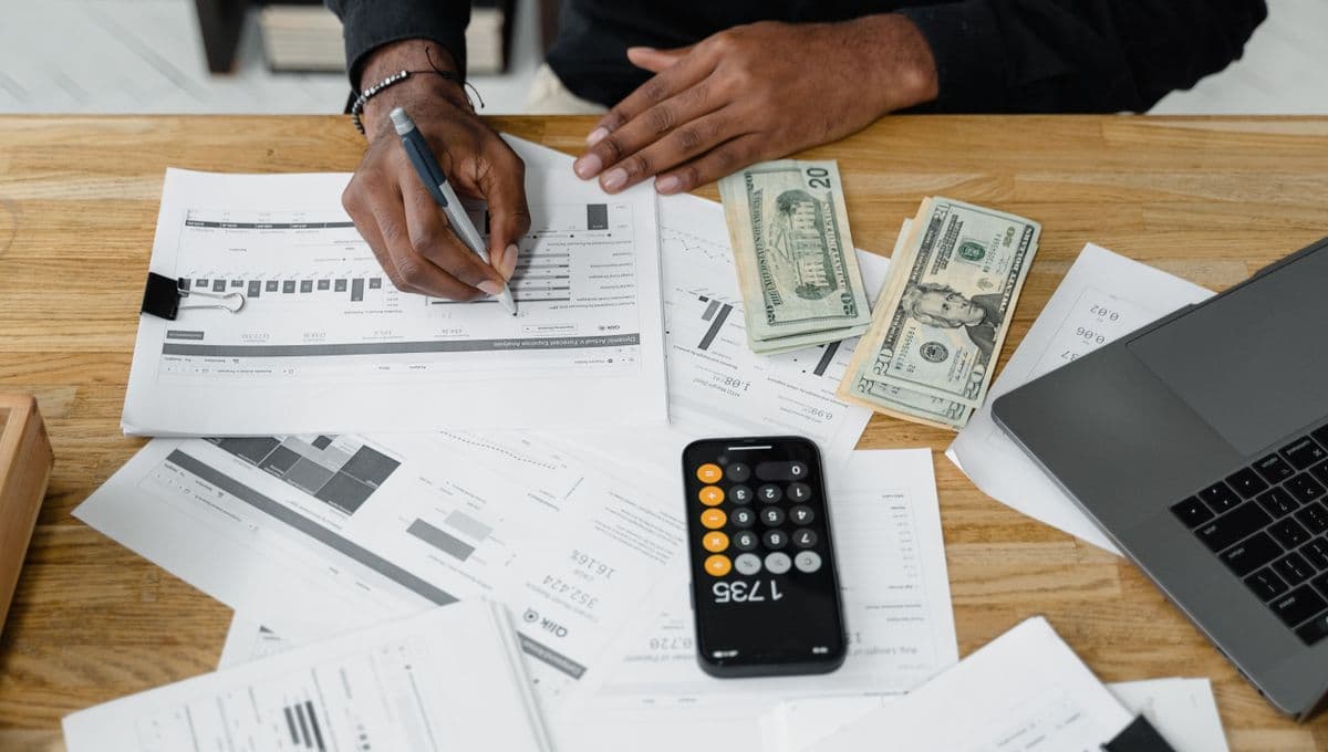 An accountant's desk with a calculator, laptop and financial paperwork
